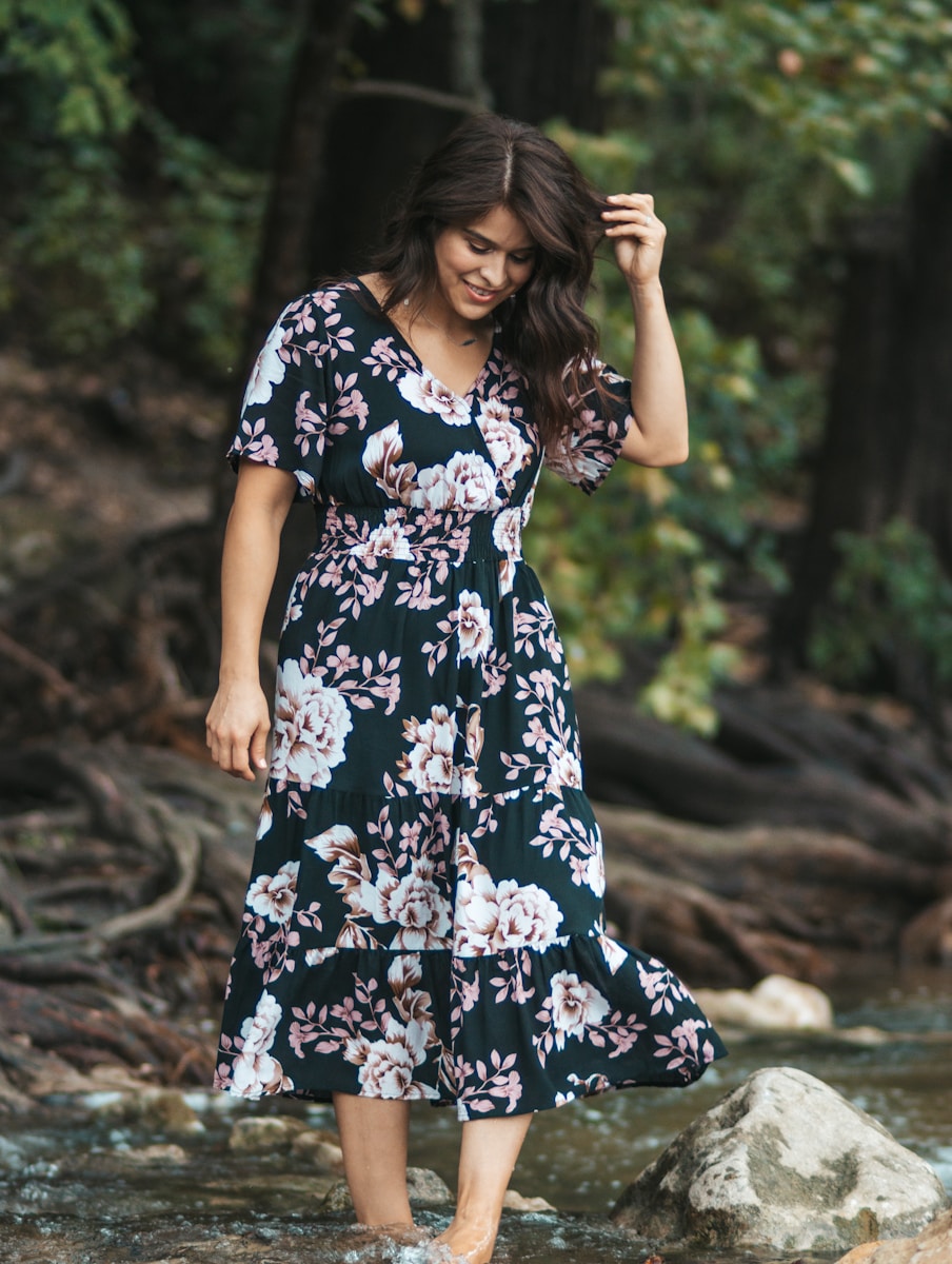 woman in black white and red floral dress standing on brown soil